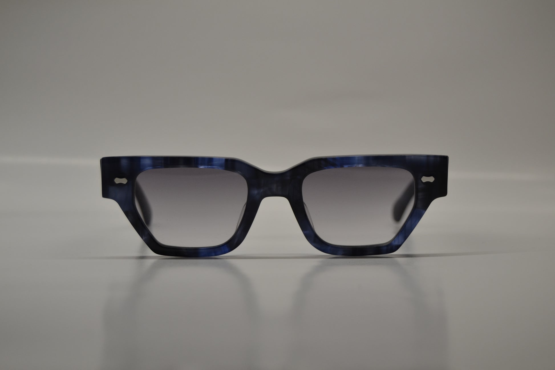 A pair of limited edition sunglasses with a blue acetate frame, polarized lenses, and UV protection.