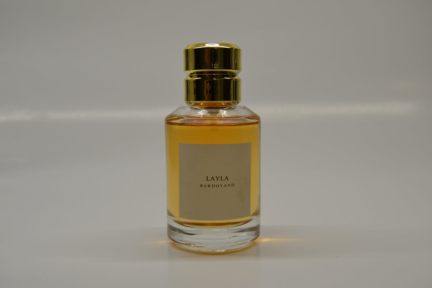 Perfume bottle with gold cap and named Layla and label on a gray background
