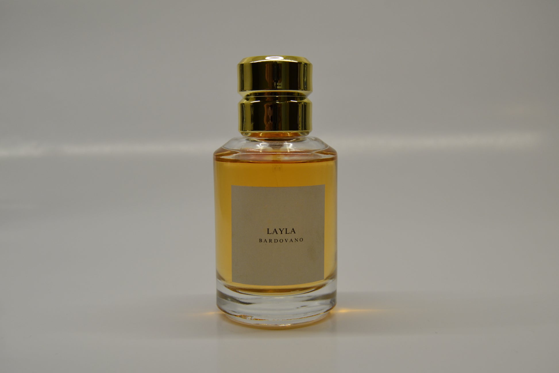 Perfume bottle with gold cap and named Layla and label on a gray background