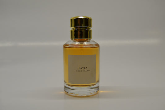 Perfume bottle with gold cap and named Layla and label on a gray background
