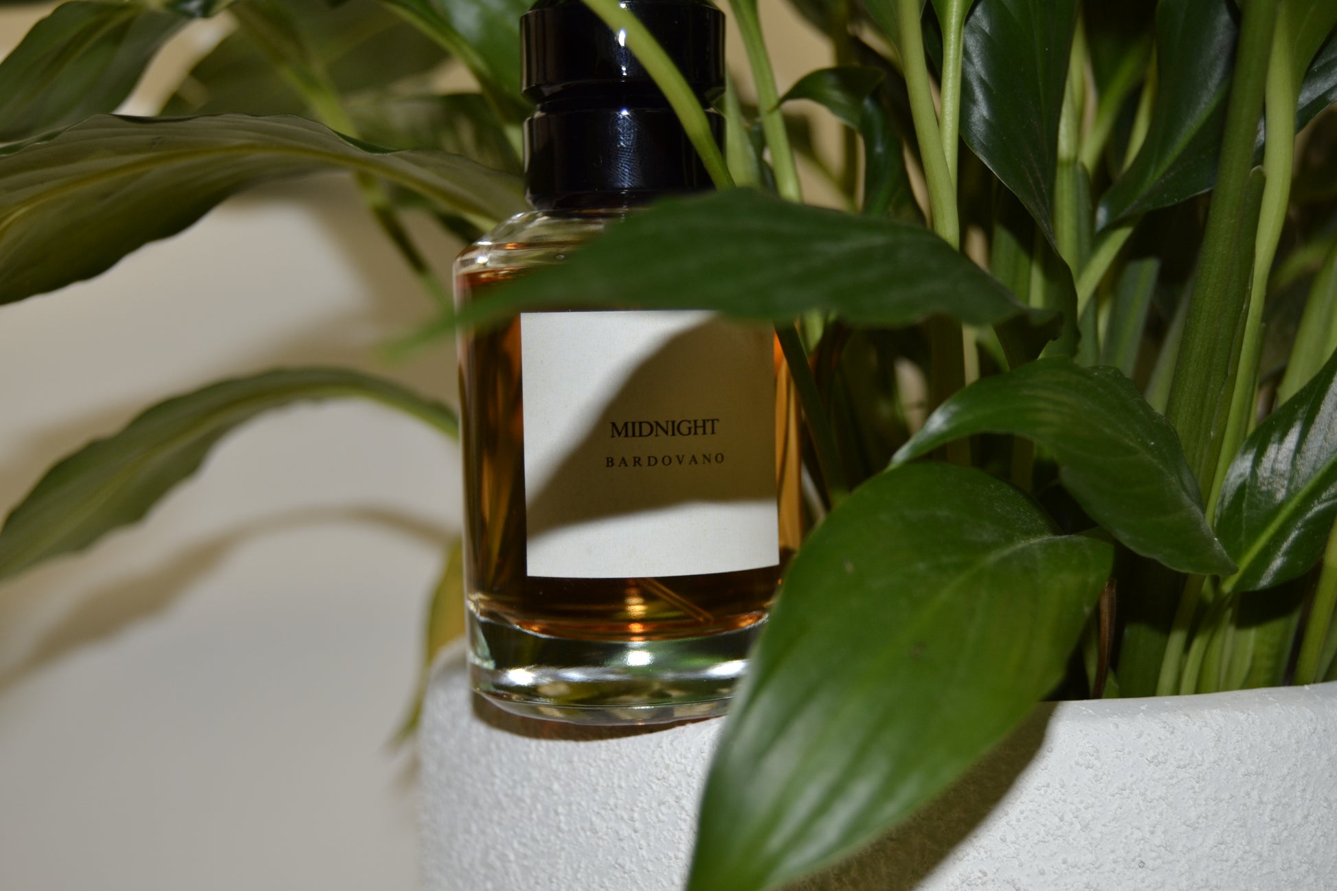 Perfume bottle labeled 'Midnight' with green leaves in the background