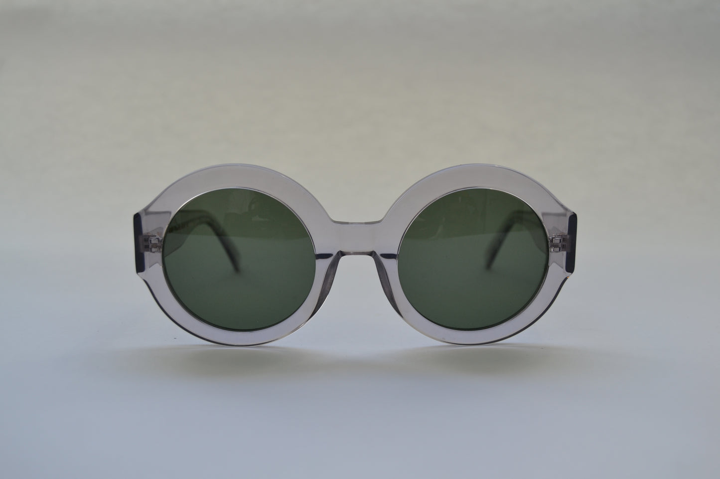 A pair of black, round-framed sunglasses with polarized lenses on a light background.