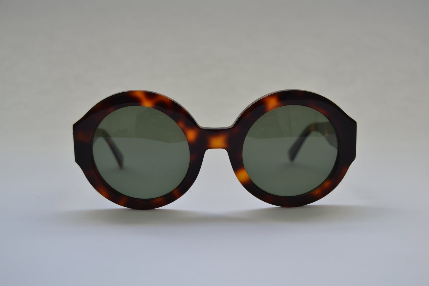 A pair of black, round-framed sunglasses with polarized lenses on a light background.