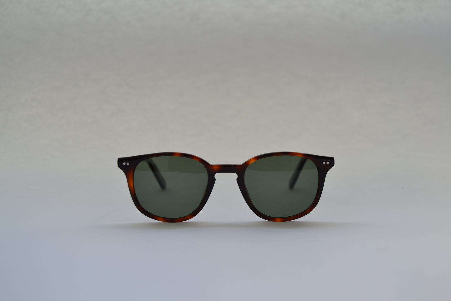 A pair of sunglasses with a black frame and patterned with a tortoiseshell design, featuring polarized lenses.