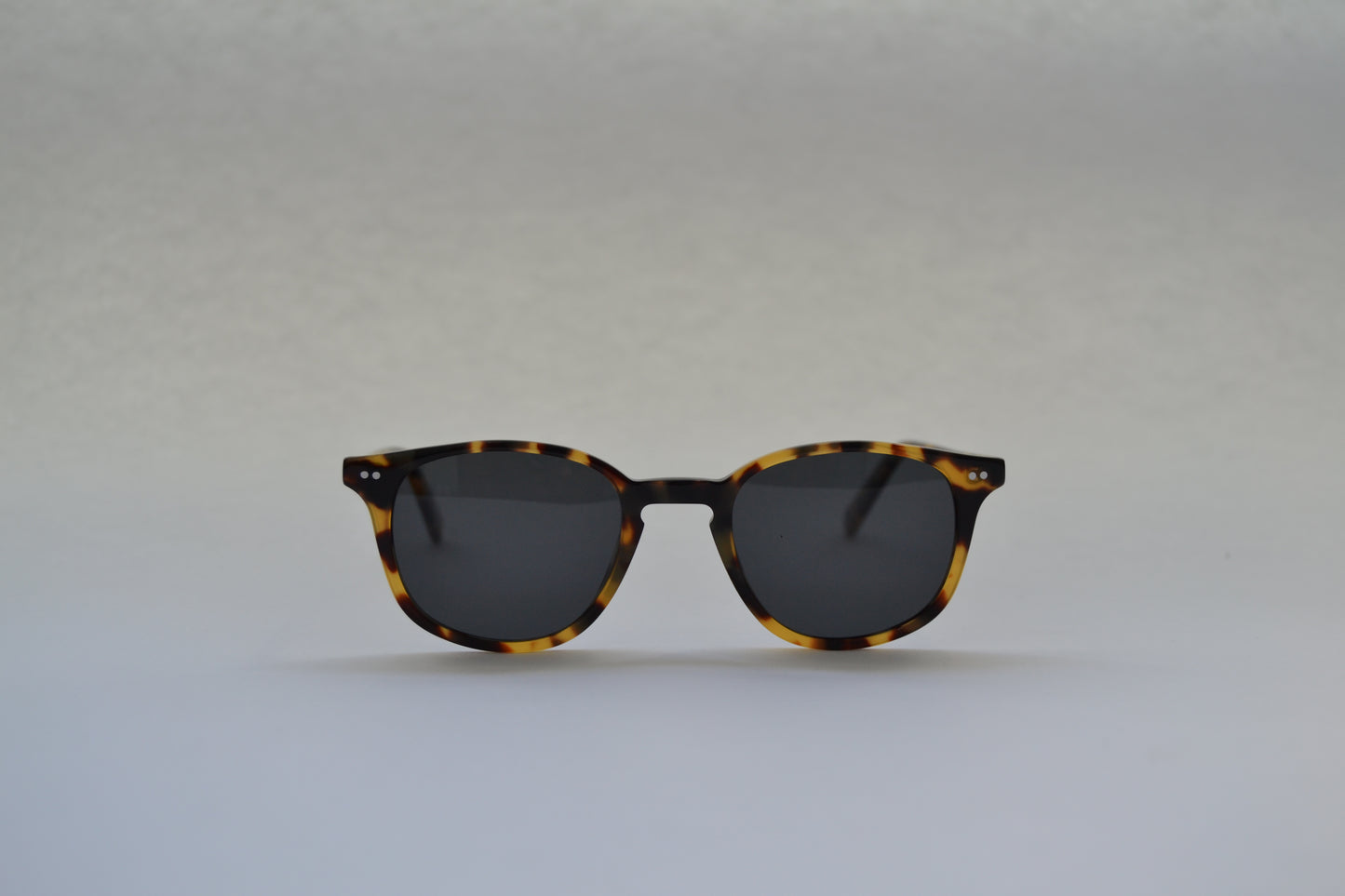 A pair of sunglasses with a black frame and patterned with a tortoiseshell design, featuring polarized lenses.